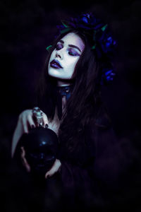 Young woman holding container against black background