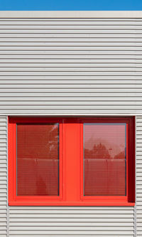 Red window amidst gray wall