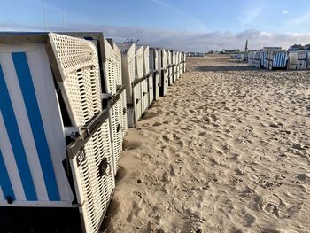 Hooded chairs on beach against sky