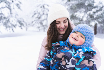 Portrait of smiling woman with daughter in snow