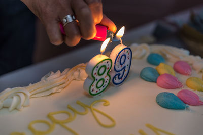 Human hand lighting candle on cake