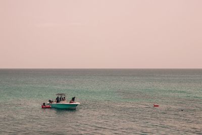 People in boat on sea against clear sky during sunset