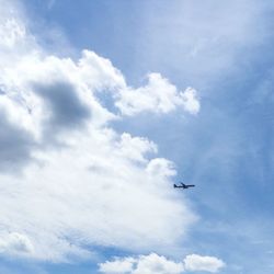 Low angle view of airplane flying against cloudy sky