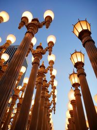 Low angle view of illuminated street lights against clear sky at sunset