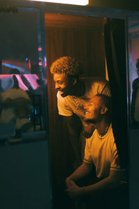 Happy male friends enjoying inside photo booth in illuminated club