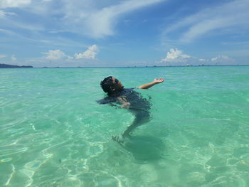 Side view of boy swimming in sea against sky during summer