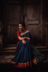 Portrait of young woman standing against wall