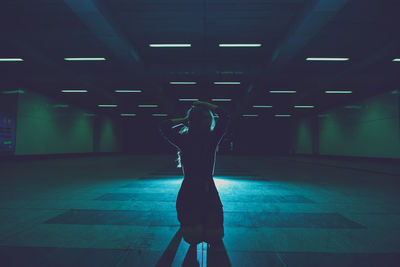 Young woman kneeling in underground walkway