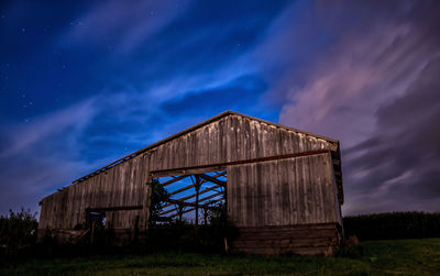 Low angle view of built structure on field against blue sky