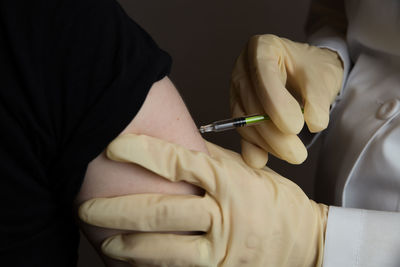 Midsection of doctor injecting syringe to patient against gray background