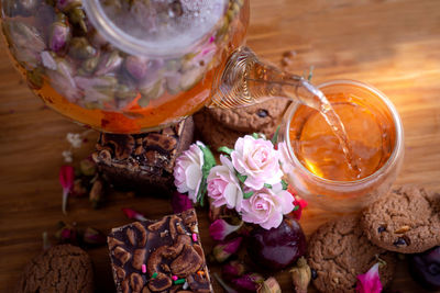 Pouring herbal tea from teapot into glass tea cup with brownie stack cake on the wooden table