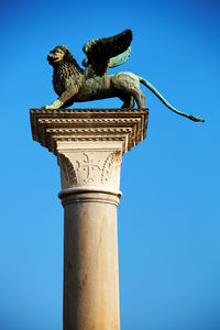 Statue of winged lion on column against clear blue sky at st mark square