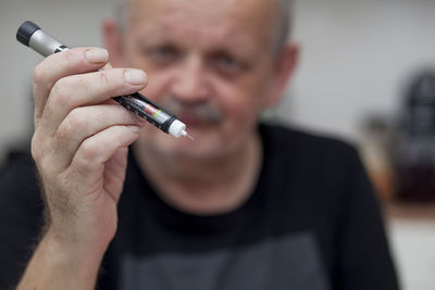 Close-up of mature man holding insulin equipment