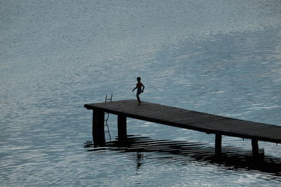 Man standing on pier over lake