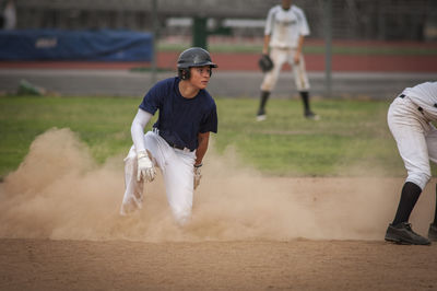 Young baseball player in cloud of dust after sliding into second base