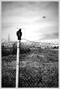 Fence on field against cloudy sky