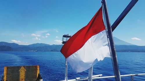 Flag on sea against mountain range