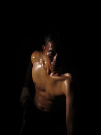 High angle portrait of sweaty shirtless man standing against black background