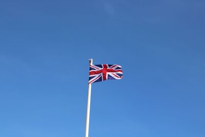 Low angle view of flag against blue sky