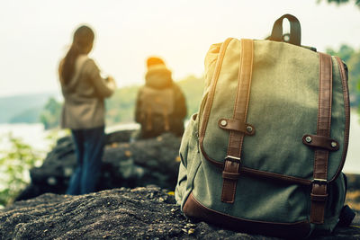 Close-up of bag on rock with people in background