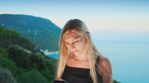 Portrait of beautiful young woman against sky