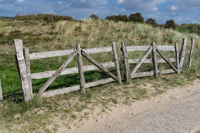 Wooden fence on field against sky