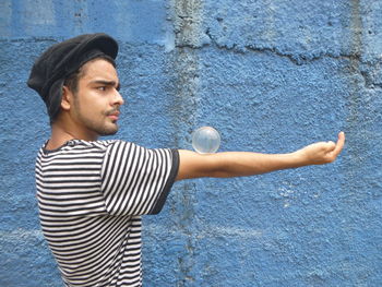 Man balancing ball on hand by wall