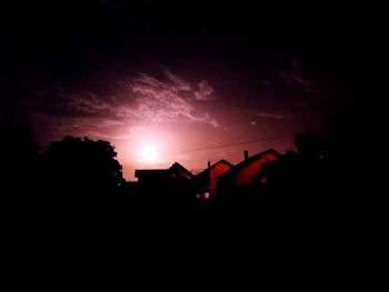 Silhouette houses against sky at night