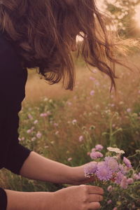 Side view of woman with flowers on field