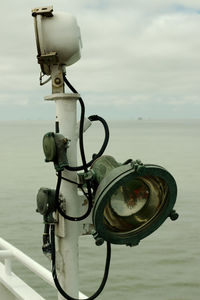 Close-up of coin-operated binoculars by sea against sky