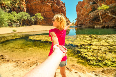 Woman holding hands of man while standing at riverbank