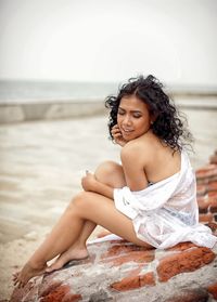 Beautiful young woman sitting on beach