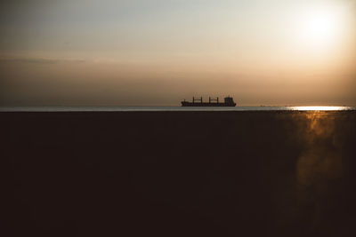 Silhouette boat sailing on sea against sky during sunset