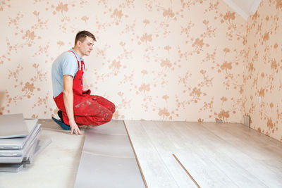 Man putting hardwood floor panels in home