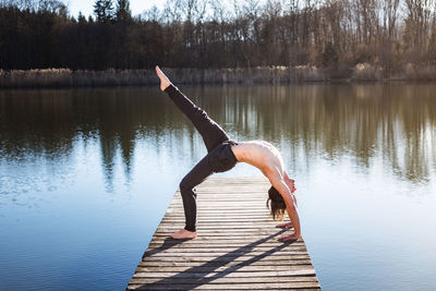 Young man exercising on jetty over lake