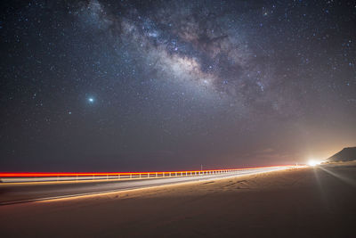 Light trails on road against sky at night