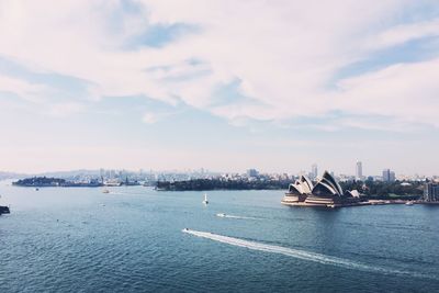 Sydney opera house by thames river against sky