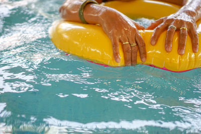 Cropped hands of person with inflatable ring swimming in pool