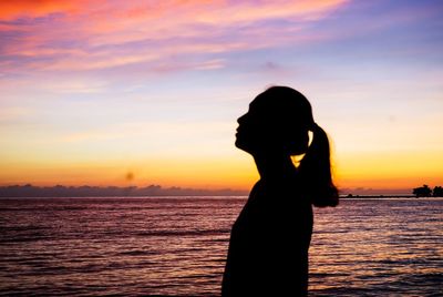 Silhouette woman standing by sea against sky during sunset