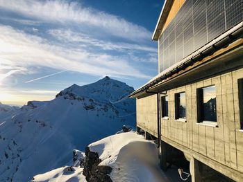 Snow covered buildings by mountain against sky