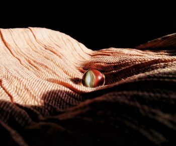 Close-up of hand holding red leaf over black background