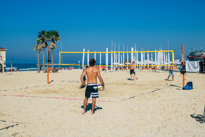 People at beach against clear sky