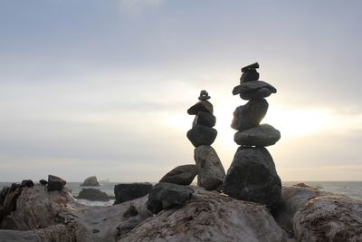 Stack of rocks by sea against sky during sunset