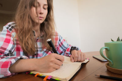 Young woman using mobile phone while sitting on table