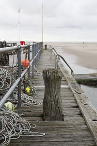 Wooden pier at beach against sky