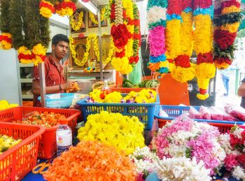 Woman standing by multi colored flowers at market stall