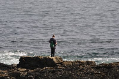 Man standing on rock looking at sea