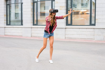 Full length of woman with arms raised in city