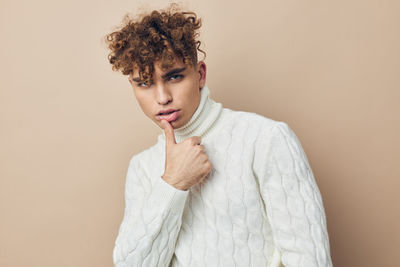 Portrait of young man standing against beige background