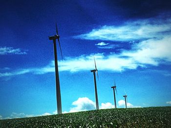 Low angle view of wind turbines in field